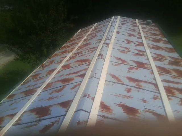 Rusted metal roof panels with new wood purlins before replacement — Storm Damage Roof Repair in Oak Grove by Roofing Brothers